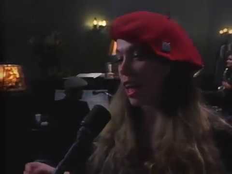 Performer wearing a red beret speaks into a microphone at an indoor event